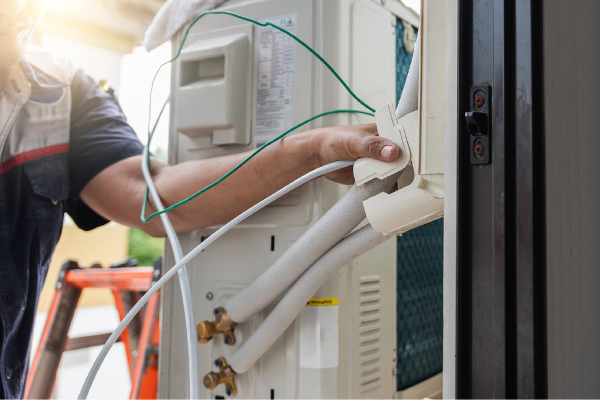 Tècnic connectant el cablejat d'una unitat exterior de climatització.